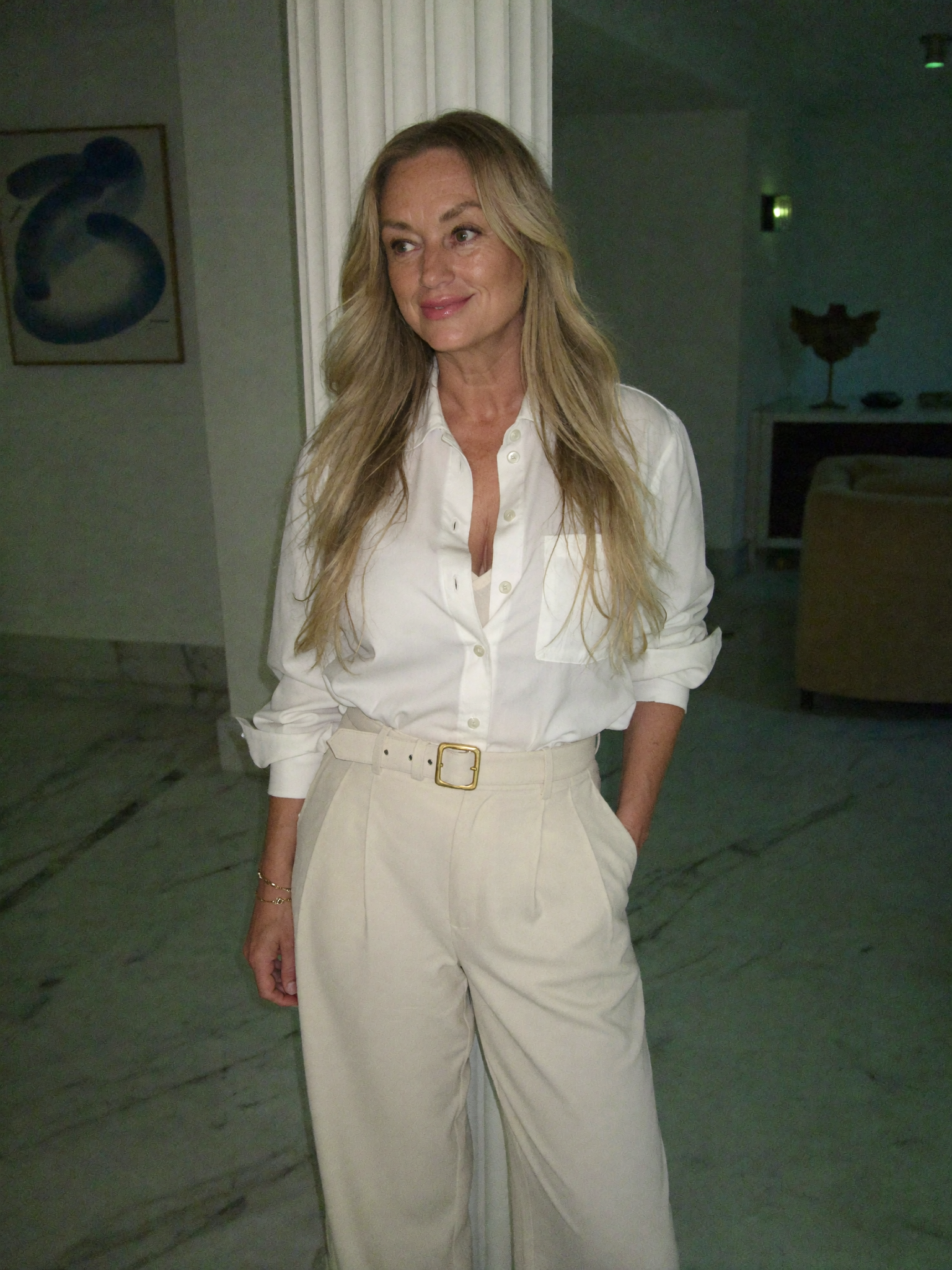 Paula Whiting, wearing a white shirt and cream trousers, standing with quiet confidence